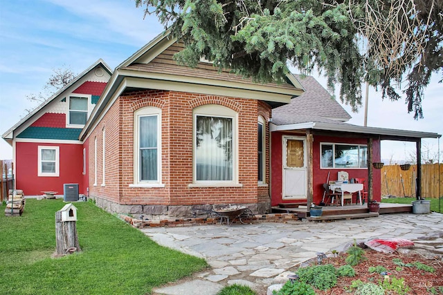 view of front of house featuring a front lawn, central air condition unit, and a patio area