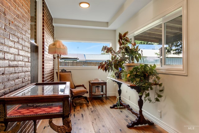 living area with hardwood / wood-style floors and brick wall