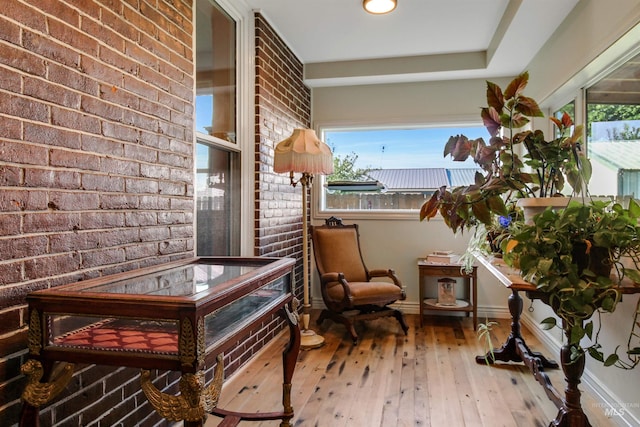 living area featuring wood-type flooring and brick wall