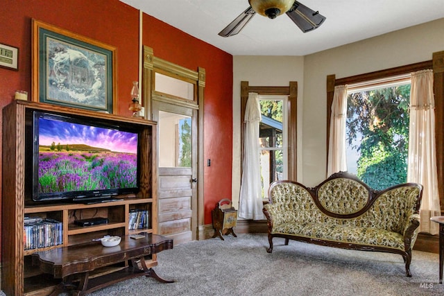 living area with carpet flooring, baseboards, and a ceiling fan