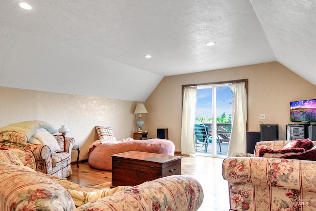 bedroom featuring a textured ceiling, lofted ceiling, light wood-type flooring, and access to exterior