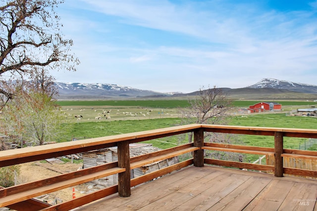 deck with a rural view, a yard, and a mountain view