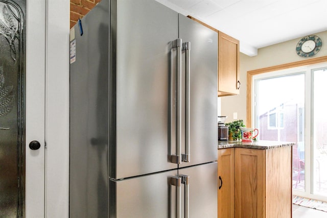 kitchen featuring high quality fridge and dark stone counters