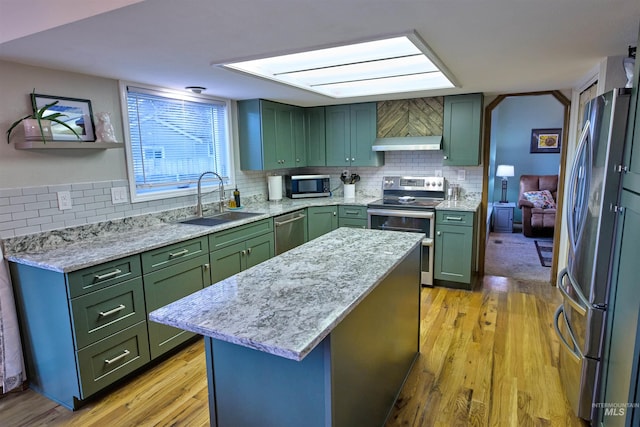 kitchen featuring light wood finished floors, a sink, appliances with stainless steel finishes, and green cabinetry