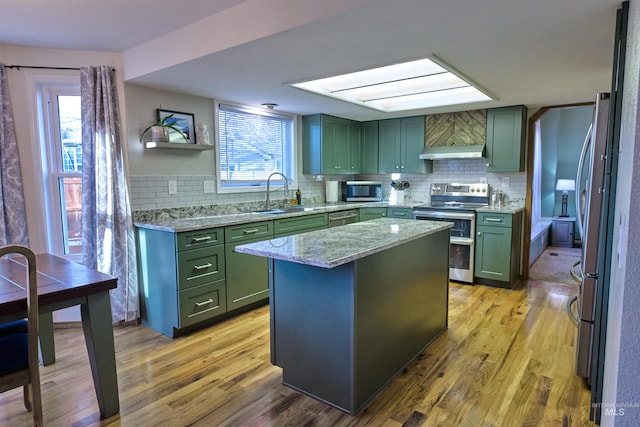 kitchen featuring a sink, light wood-style flooring, stainless steel appliances, and green cabinetry