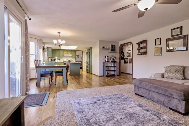 living room with light wood finished floors and ceiling fan with notable chandelier