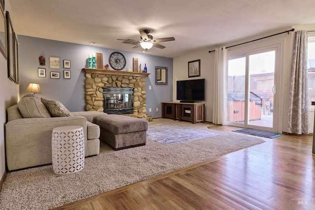 living area with a fireplace, wood finished floors, and ceiling fan