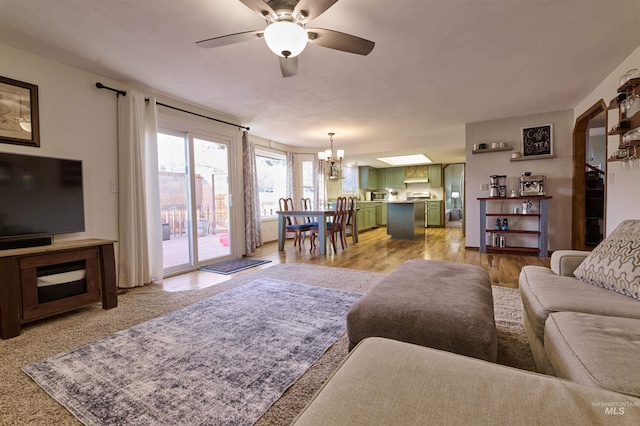 living room with ceiling fan with notable chandelier and light wood-type flooring