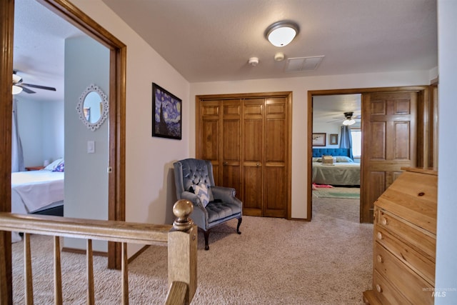 sitting room featuring visible vents, ceiling fan, and carpet