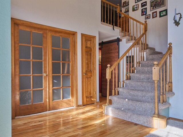 stairway with a high ceiling, a barn door, and wood finished floors