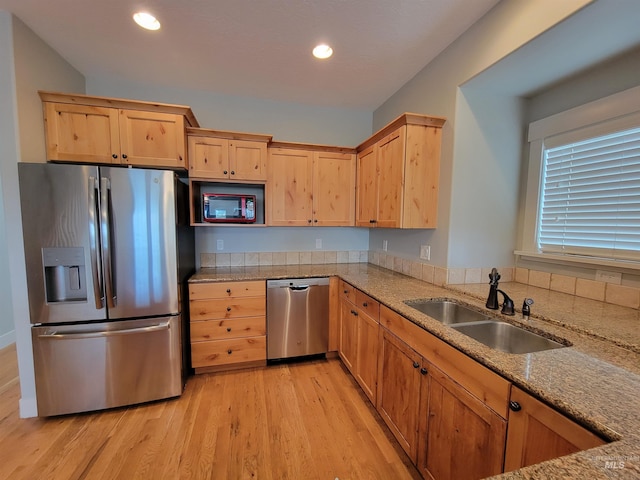 kitchen with sink, light stone counters, light brown cabinets, appliances with stainless steel finishes, and light hardwood / wood-style floors