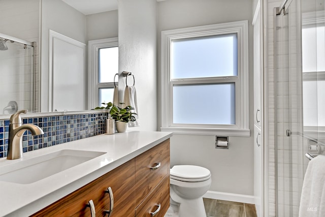 bathroom featuring vanity, a shower with shower door, toilet, and tasteful backsplash