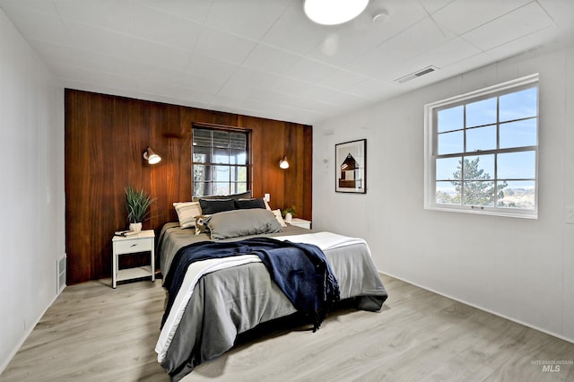 bedroom featuring wooden walls and light hardwood / wood-style flooring