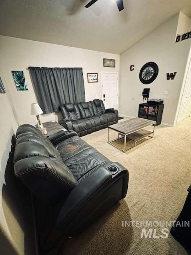 carpeted living room with ceiling fan and vaulted ceiling