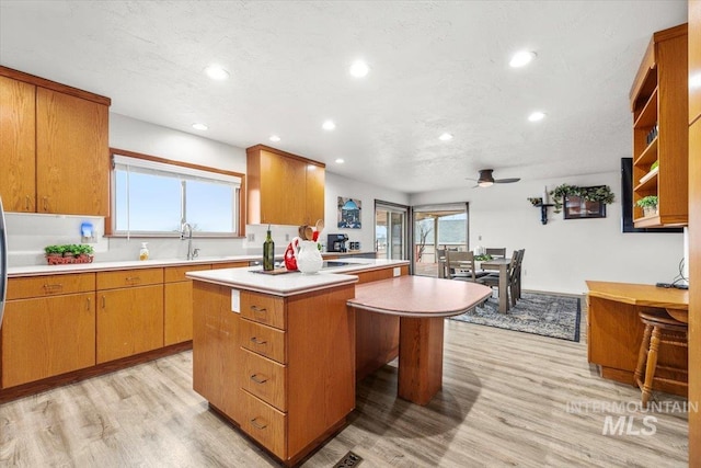 kitchen featuring a sink, light wood-type flooring, light countertops, and a wealth of natural light