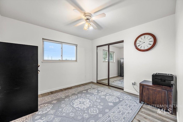 bedroom featuring a ceiling fan, a closet, baseboards, and wood finished floors