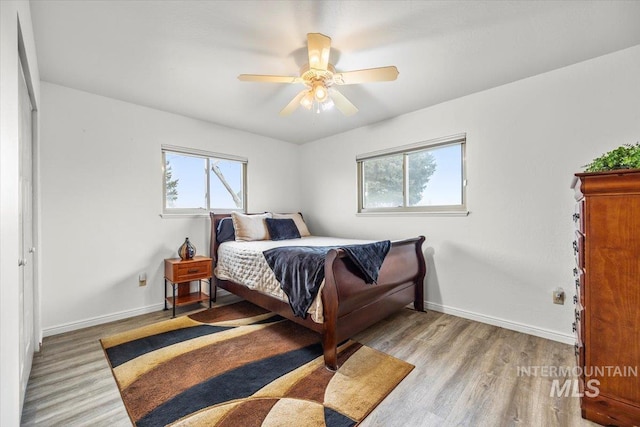 bedroom featuring multiple windows, light wood-style flooring, and baseboards