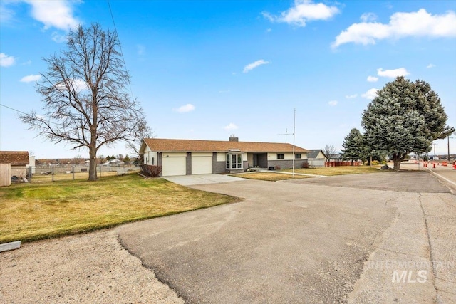 single story home with a chimney, an attached garage, a front yard, fence, and driveway