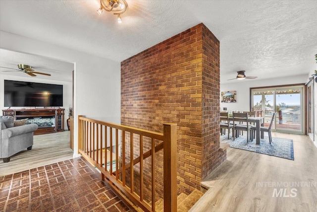 corridor featuring a textured ceiling, an upstairs landing, and wood finished floors