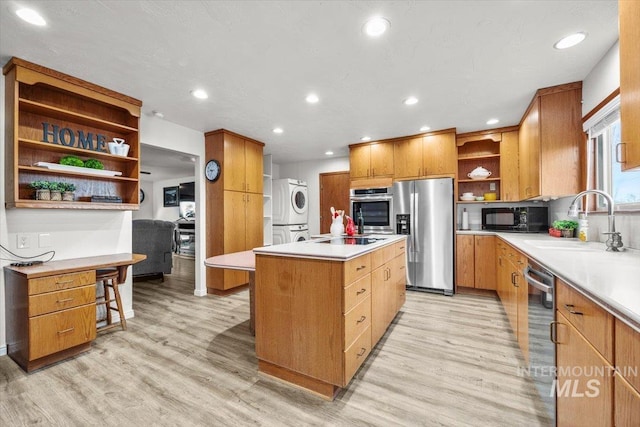 kitchen featuring a center island, open shelves, stacked washer / dryer, a sink, and black appliances