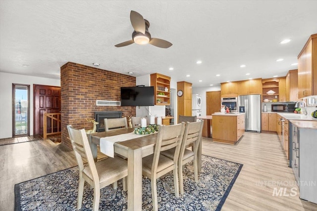 dining space featuring stacked washer and dryer, recessed lighting, a textured ceiling, and light wood finished floors