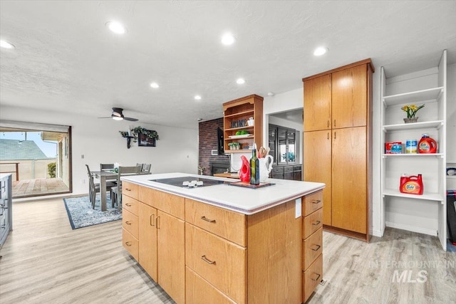 kitchen featuring a ceiling fan, a center island, black electric stovetop, light wood-style floors, and open shelves