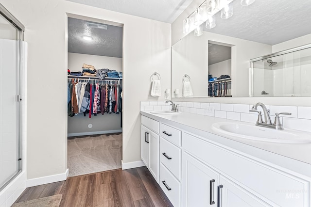 10255 W Gladiola St, Star, ID 83669 - bathroom featuring a textured ceiling, a walk in closet, a stall shower, wood finished floors, and double vanity