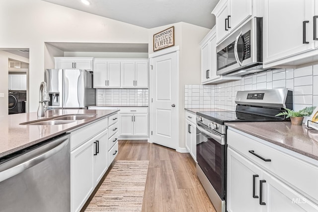 10255 W Gladiola St, Star, ID 83669 - kitchen featuring appliances with stainless steel finishes, light wood-style floors, washer / clothes dryer, light stone countertops, and white cabinets
