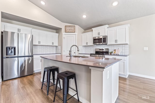 10255 W Gladiola St, Star, ID 83669 - kitchen with stainless steel appliances, a kitchen breakfast bar, lofted ceiling, light wood-style floors, and white cabinetry