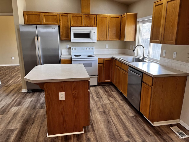 kitchen with visible vents, a kitchen island, appliances with stainless steel finishes, dark wood-style flooring, and a sink