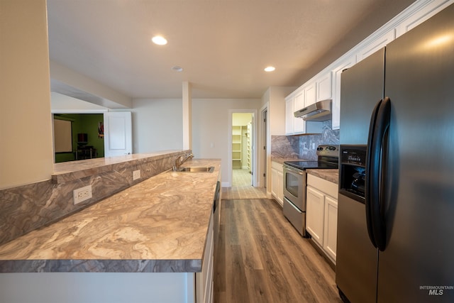 kitchen featuring under cabinet range hood, dark wood finished floors, decorative backsplash, appliances with stainless steel finishes, and a sink