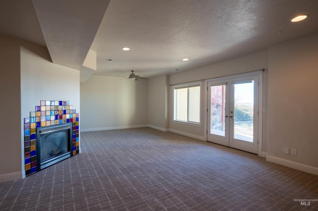 interior space with a textured ceiling, a glass covered fireplace, recessed lighting, carpet floors, and baseboards