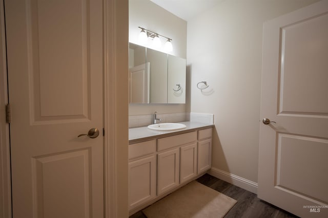 bathroom with baseboards, backsplash, wood finished floors, and vanity