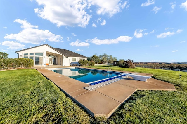 pool featuring a diving board, a patio, a lawn, and fence