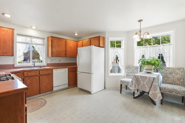 kitchen featuring an inviting chandelier, a sink, a wealth of natural light, and white appliances