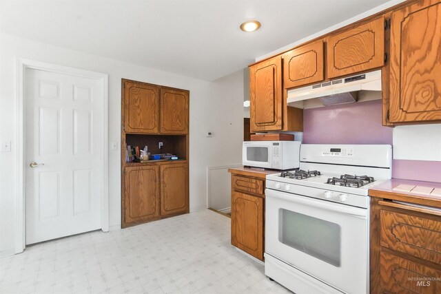 kitchen with white appliances, light countertops, brown cabinetry, light floors, and under cabinet range hood