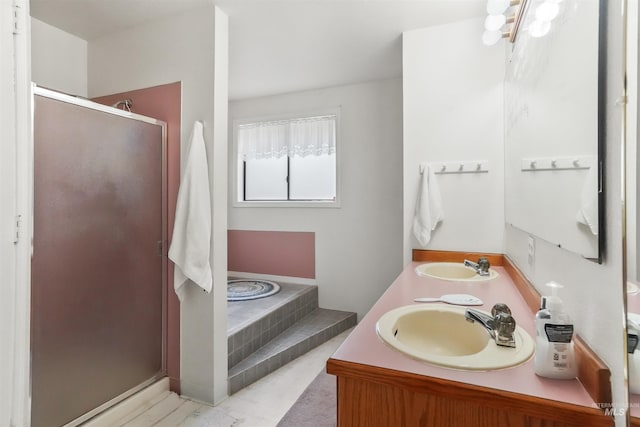 full bath with double vanity, a sink, a garden tub, and a stall shower