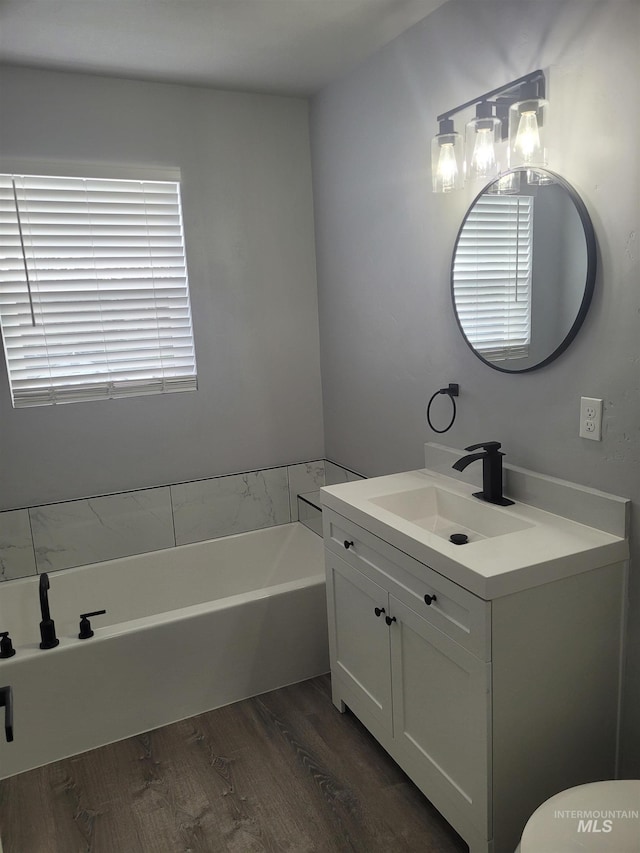 bathroom with hardwood / wood-style floors, a bath, vanity, and a healthy amount of sunlight