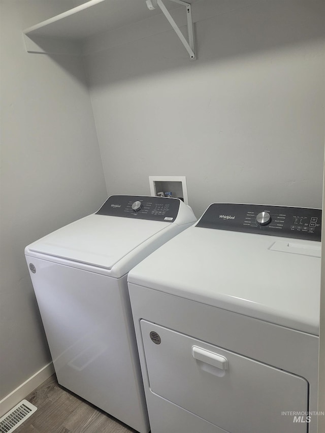 washroom with washing machine and clothes dryer and hardwood / wood-style floors