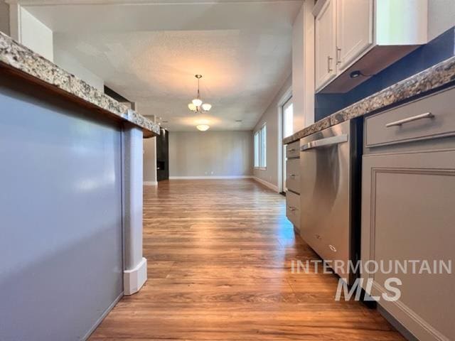 kitchen featuring white cabinets, dishwasher, light wood-type flooring, and decorative light fixtures