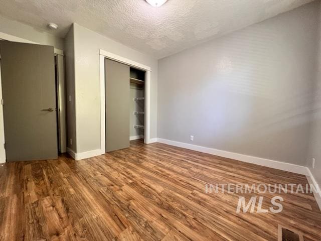 unfurnished bedroom featuring wood-type flooring, a textured ceiling, and a closet