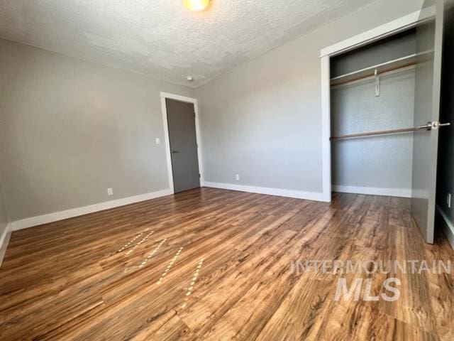 unfurnished bedroom with wood-type flooring, a textured ceiling, and a closet