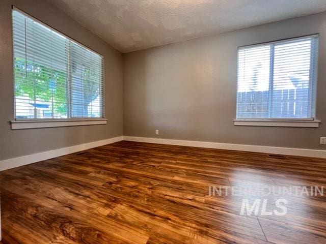 unfurnished room with wood-type flooring and a textured ceiling