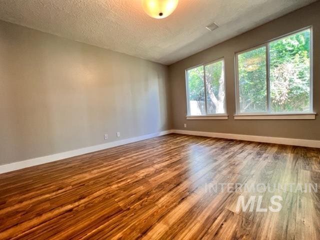 unfurnished room featuring wood-type flooring and a textured ceiling