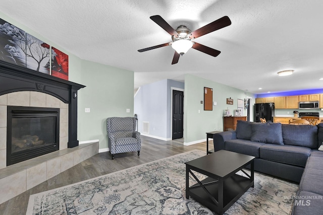 living room featuring hardwood / wood-style flooring, a tile fireplace, and a textured ceiling