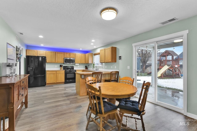 dining area with plenty of natural light, sink, and light hardwood / wood-style floors