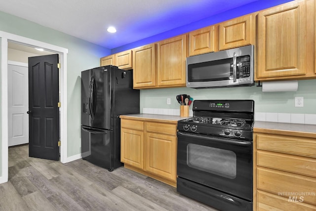 kitchen with light brown cabinets, light hardwood / wood-style floors, and black appliances