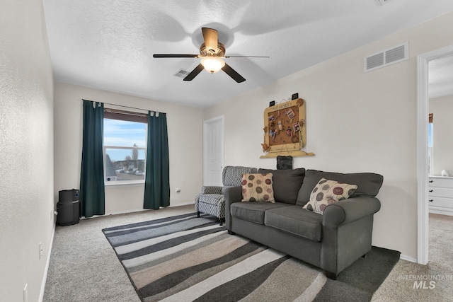 living room with light carpet, ceiling fan, and a textured ceiling