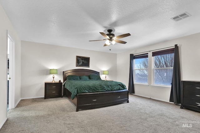 carpeted bedroom featuring ceiling fan and a textured ceiling