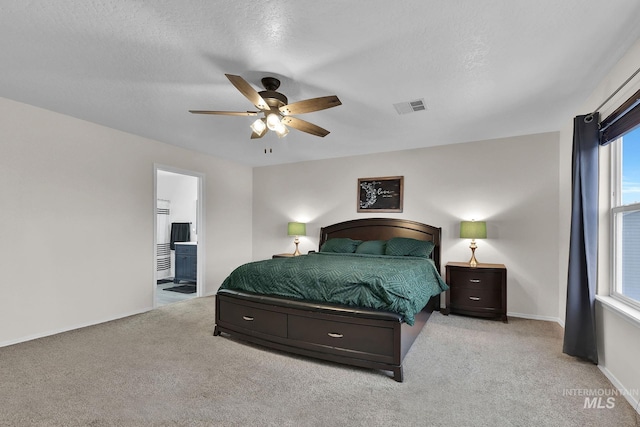 carpeted bedroom featuring ceiling fan, ensuite bath, and a textured ceiling